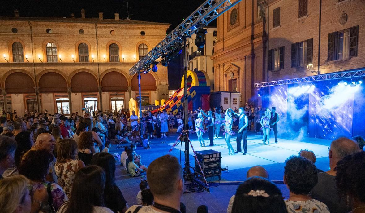 Spettacolo serale con ballerini e folla in piazza nel centro storico di Imola durante Imola di Mercoledì 2026