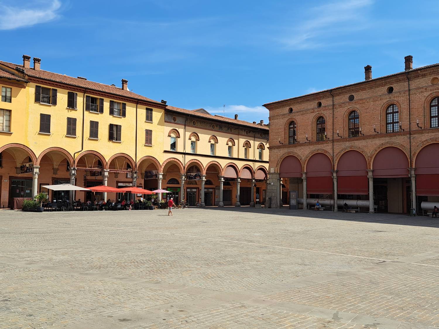 Piazza Matteotti a Imola con i portici e i tavolini dei locali sotto gli ombrelloni